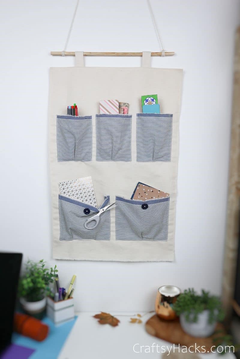 DIY wall hanger pocket organizer with blue striped pockets.