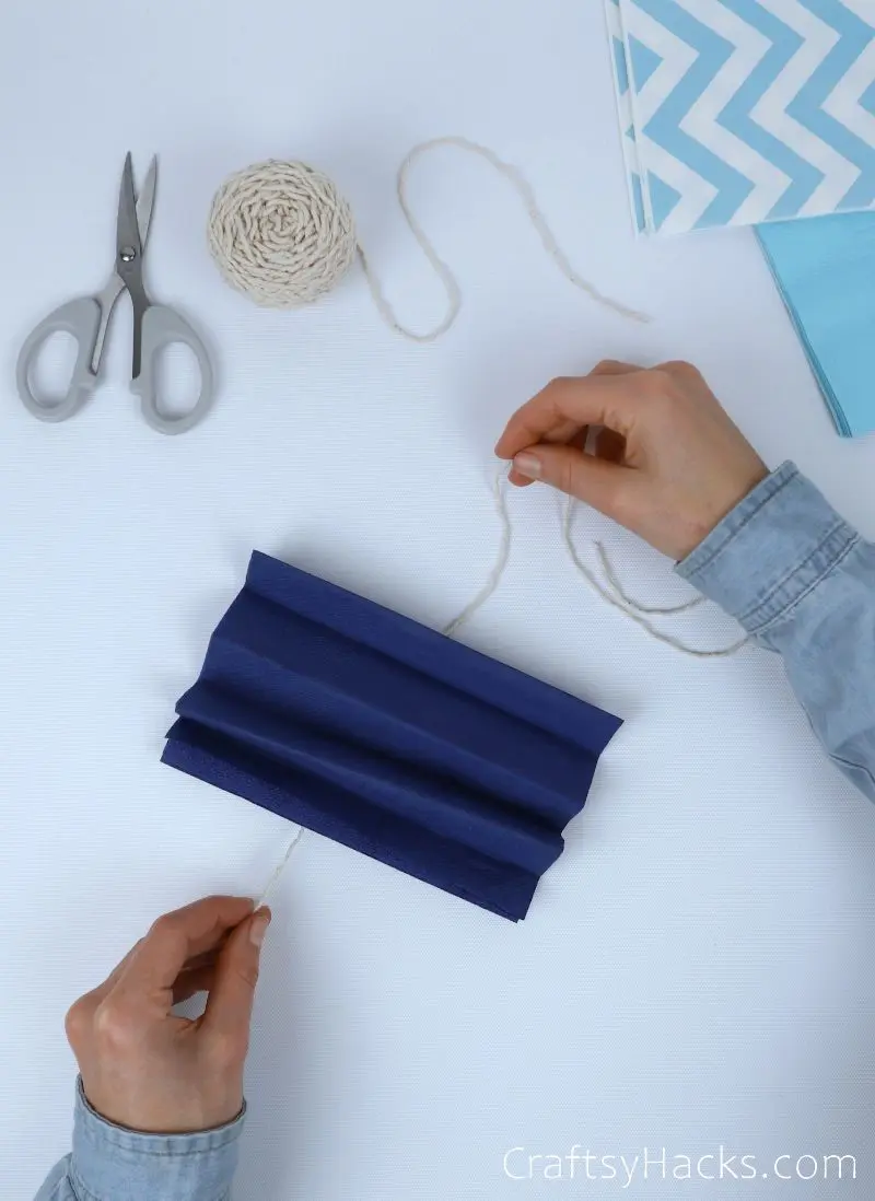 wrapping string around folded tissue paper