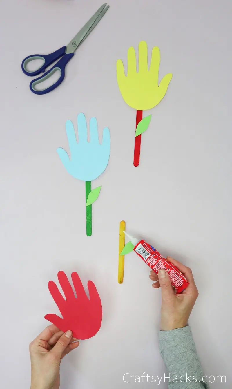 glueing handprints to popsicle sticks