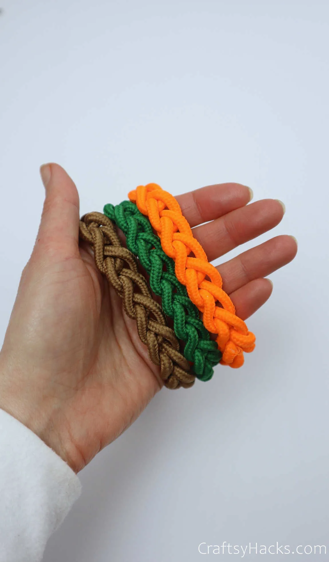 holding brown, green, and orange bracelets