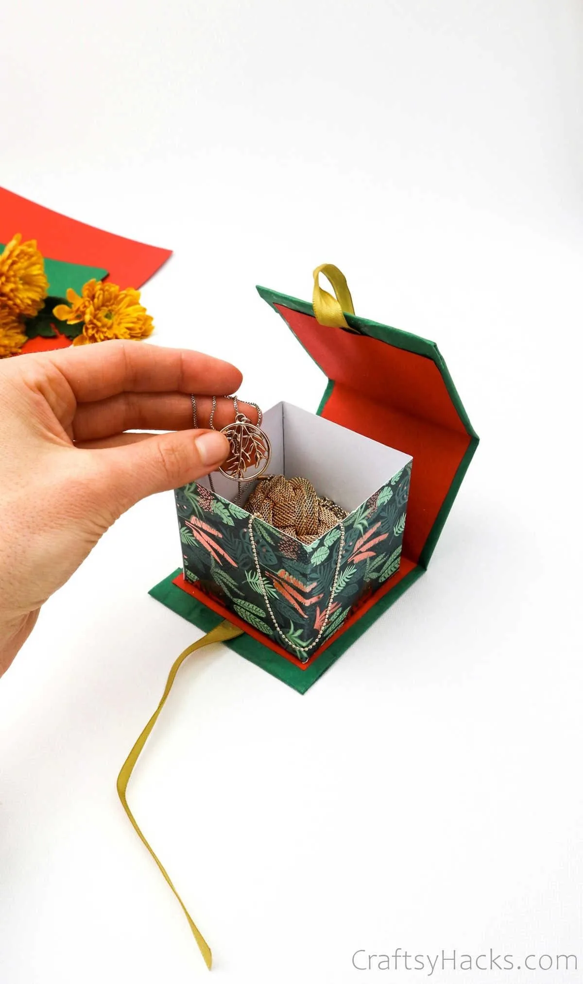 holding necklace above gift box