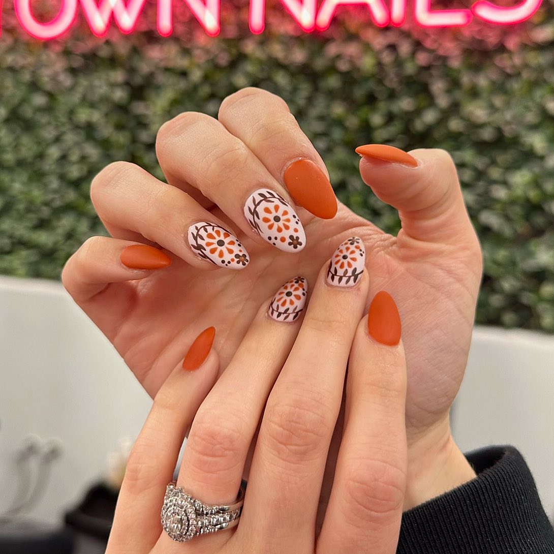 18. Floral Designs on Orange Nails